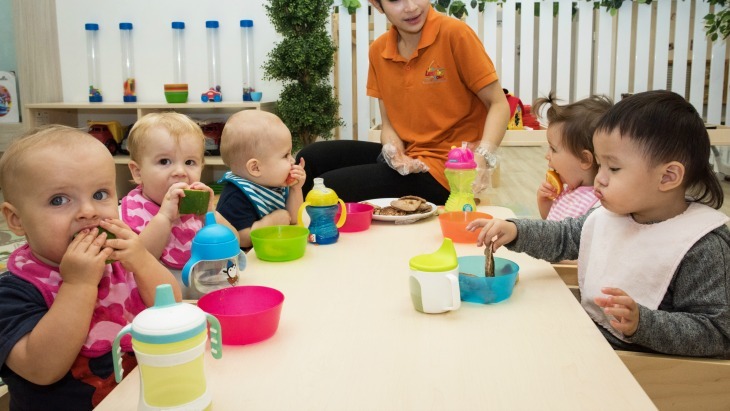pest free day care. toddlers are sitting at a table eating their lunch.