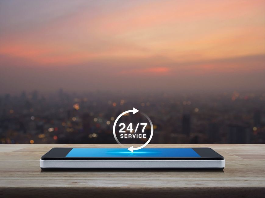 a cell phone with a city in the background. 24/7 service and open 7 days a week