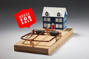 a toy house on a mouse snap trap. selling your home with a house for sale sign