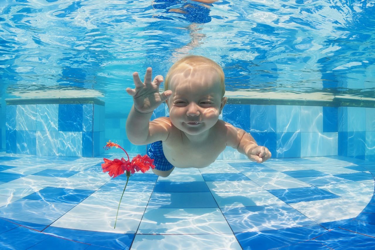 a small child swimming under water away from water bugs