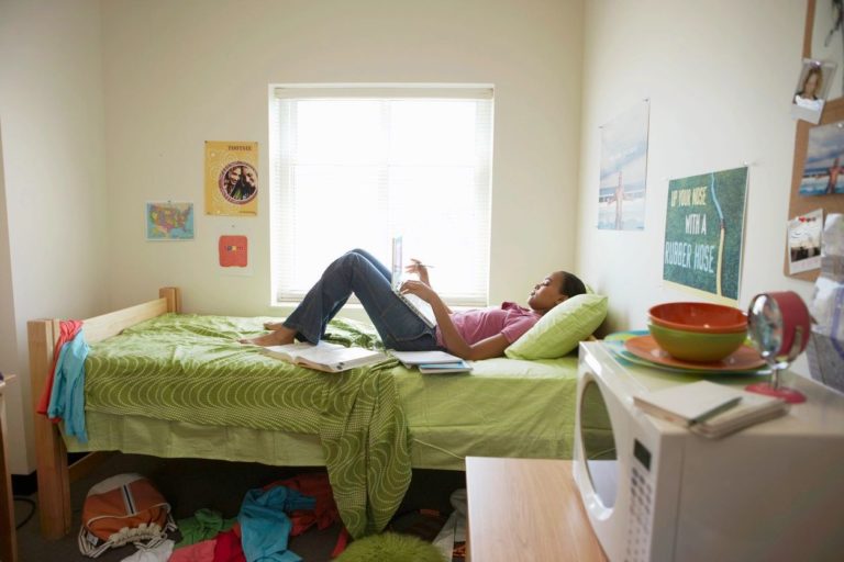 A girl lying on a bed in a student dorm. Bed bugs hitchhiking their way into her room.
