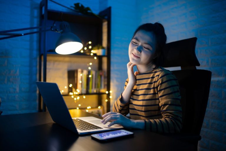 A girl looking at her laptop scratching because she needs a flea treatment